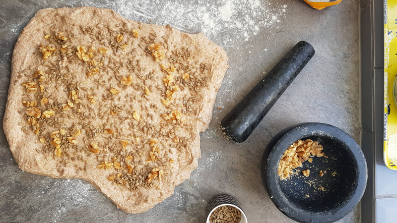 In this picture half of the walnuts and half of the seeds are evenly distributed on the stretched dough.